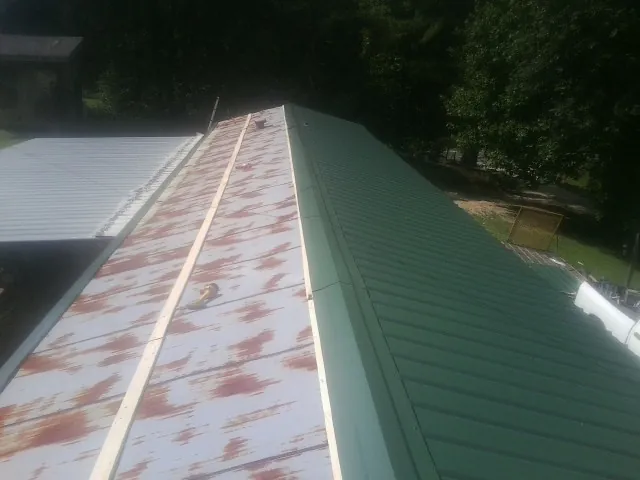 Old rusted panels beside newly installed green metal roofing — Wind Damage Roof Repair by Roofing Brothers in Armagh