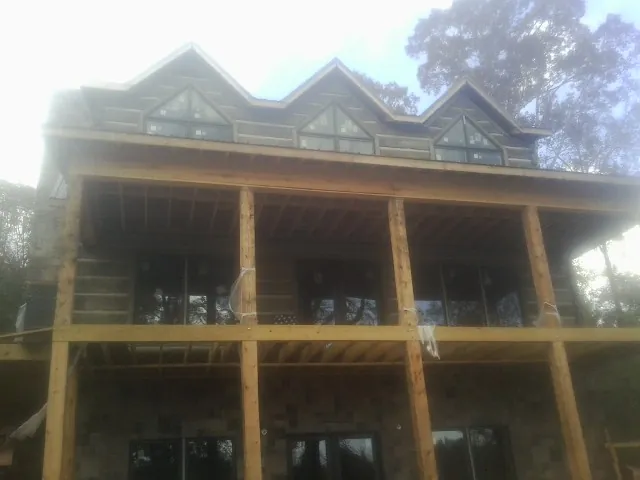 Dormers and porch framing on a large log home under construction — Roof Coating work by our crew in Armagh