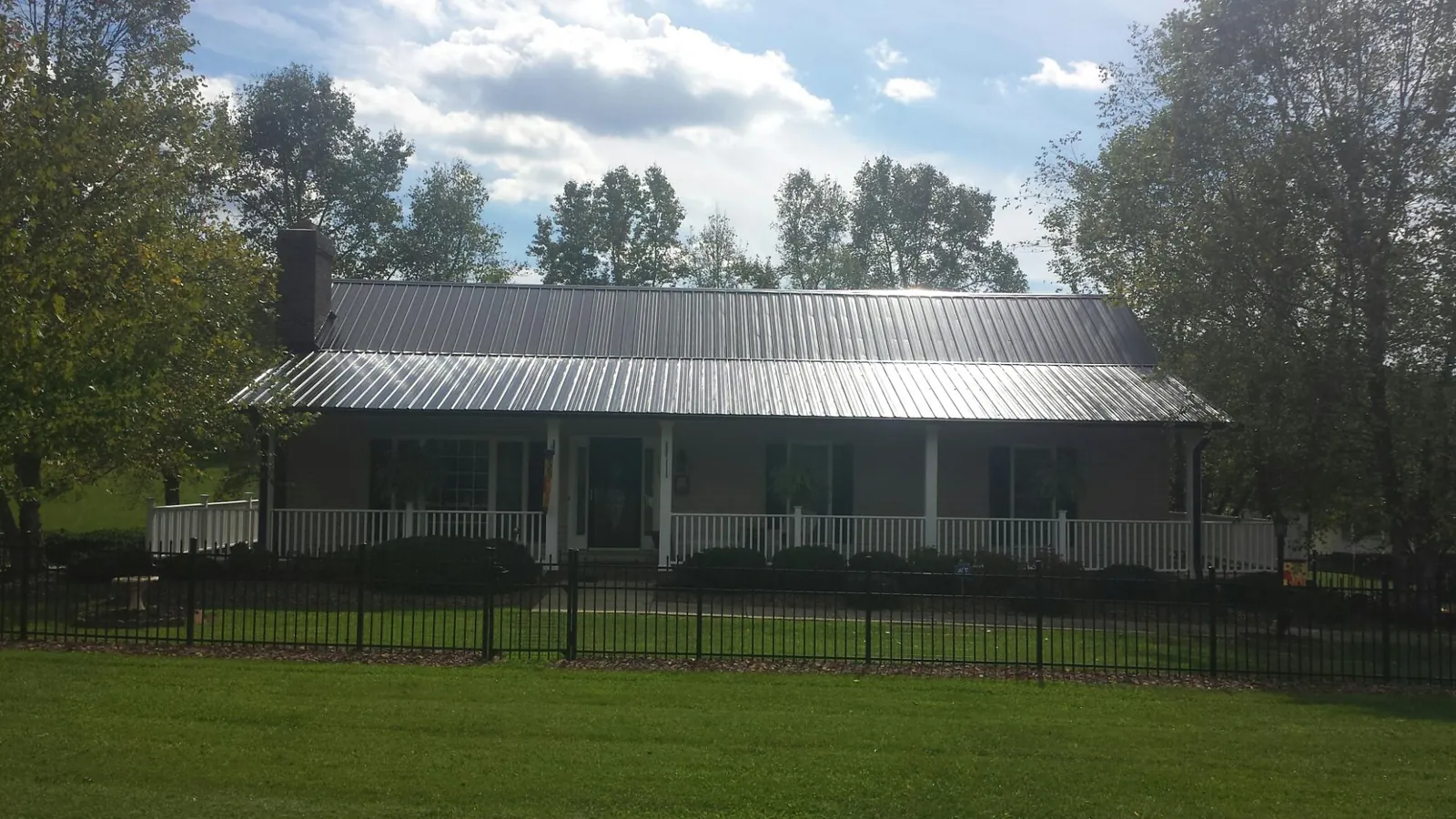 Gray metal roof on a brick ranch with a full width front porch — Gutter Guard Installation work by our crew in Armagh