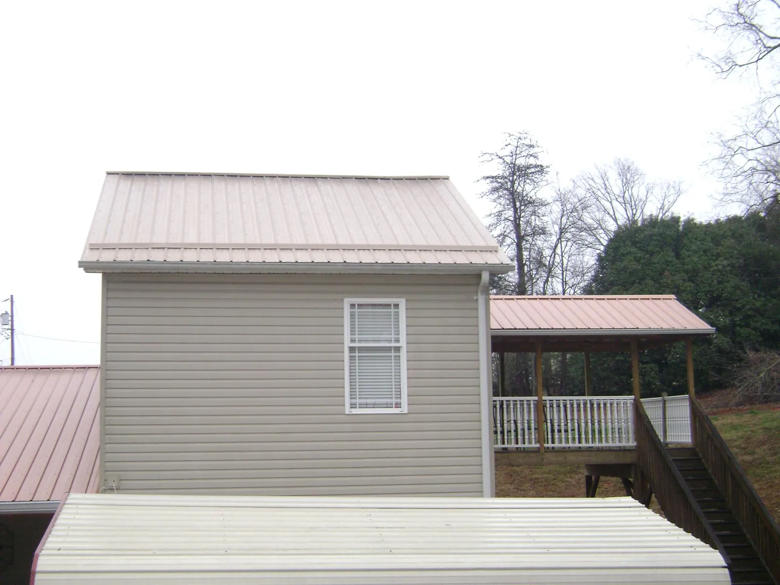 Tan metal roofs on a two story addition and attached porch, from a Roof Replacement job in Armagh