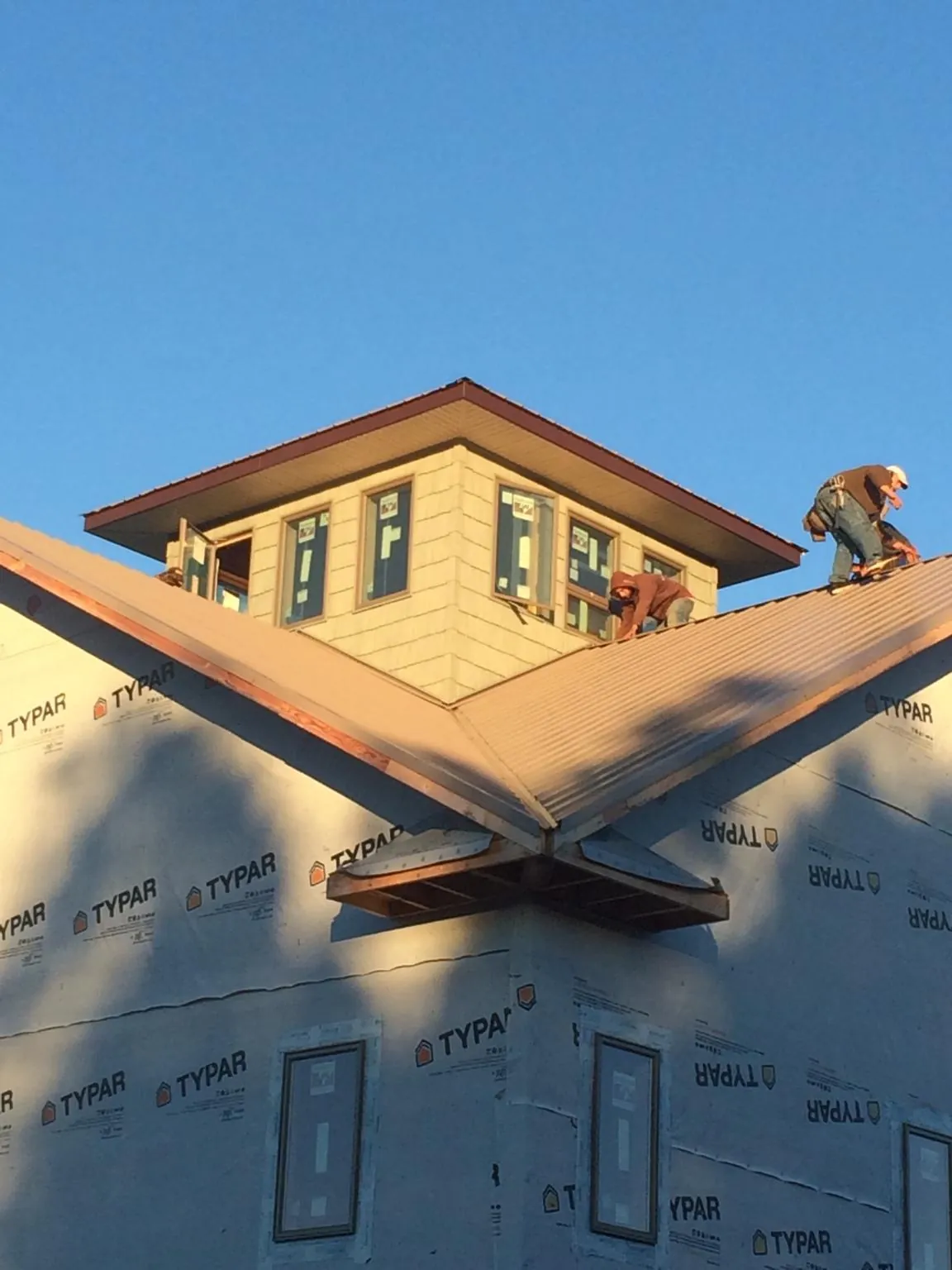 Roofers working around a rooftop cupola on a new metal roof at sunset — Roof Waterproofing in Armagh by Roofing Brothers